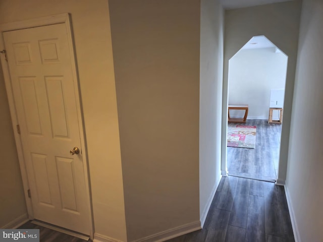 corridor featuring dark wood-type flooring and baseboards