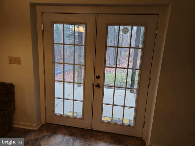 entryway with baseboards, french doors, plenty of natural light, and stone finish floor