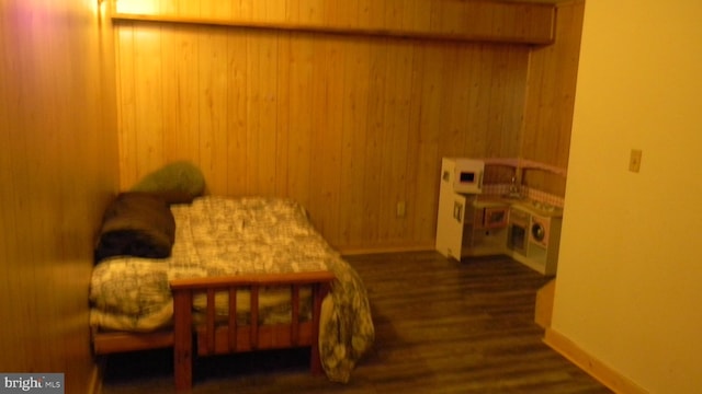 bedroom featuring dark wood-type flooring and wood walls