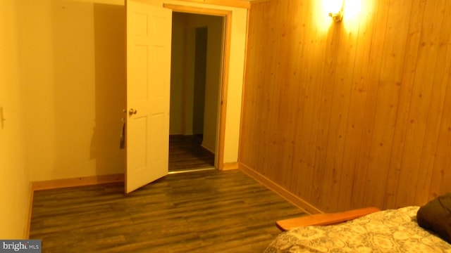 unfurnished bedroom featuring wood walls and dark hardwood / wood-style flooring