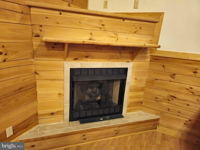 details with wood walls and a tiled fireplace