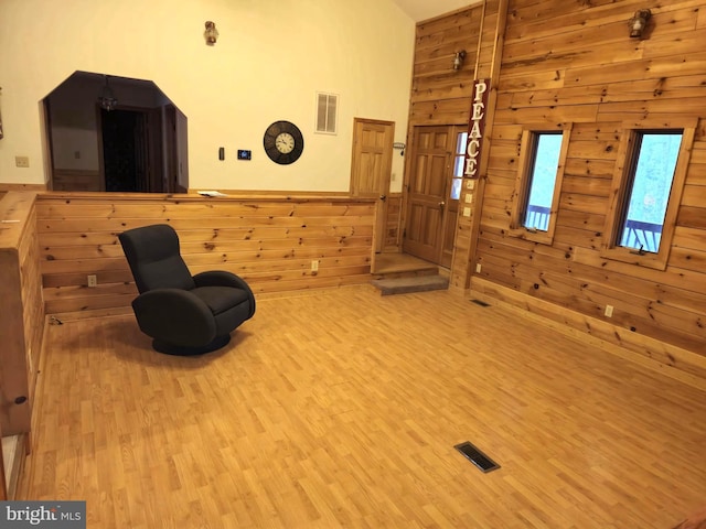 sitting room featuring wood walls, visible vents, and wood finished floors