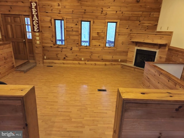 unfurnished living room with wooden walls, a fireplace, visible vents, and wood finished floors
