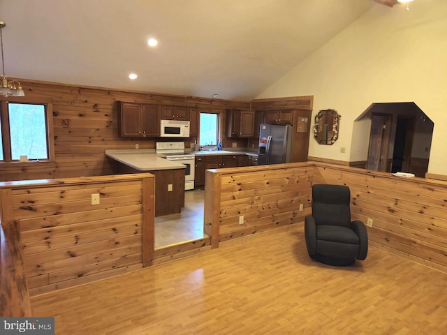 kitchen with lofted ceiling, light wood-style flooring, white appliances, a peninsula, and light countertops
