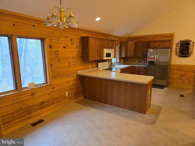 kitchen with a sink, wood walls, white appliances, visible vents, and a chandelier