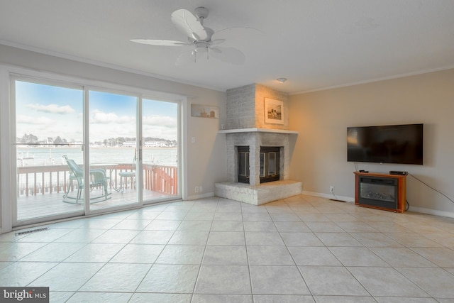 unfurnished living room featuring ceiling fan, a large fireplace, ornamental molding, and light tile patterned floors