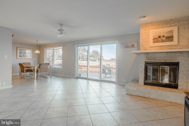 unfurnished living room featuring ceiling fan, a fireplace, light tile patterned flooring, and crown molding