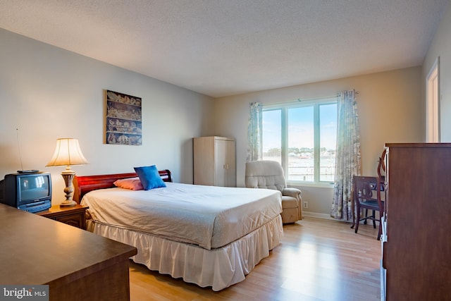 bedroom with light hardwood / wood-style floors and a textured ceiling