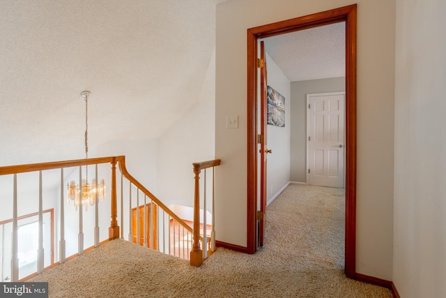 hallway with a textured ceiling, carpet floors, and vaulted ceiling