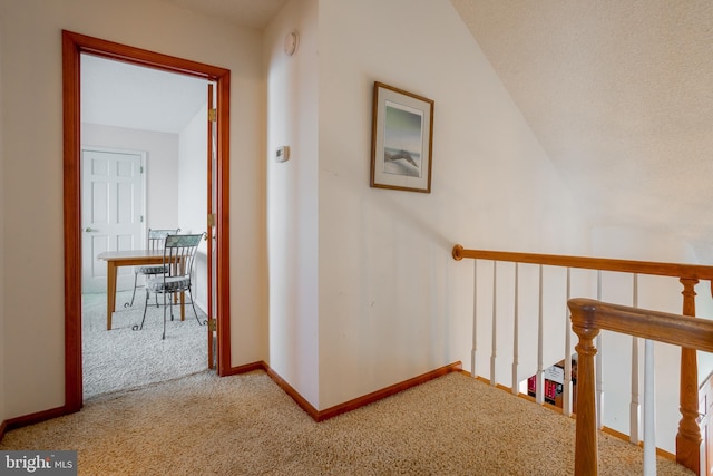 hallway with carpet floors and vaulted ceiling