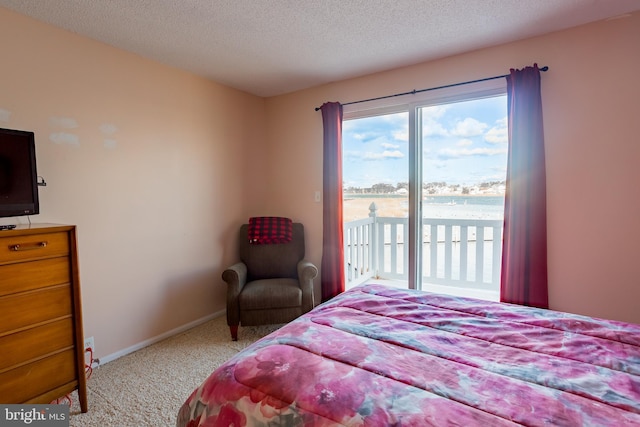 bedroom with light carpet, a textured ceiling, access to outside, and a water view