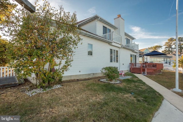 back of property with a yard, a balcony, and a deck