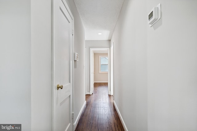 corridor with a textured ceiling and dark wood-type flooring