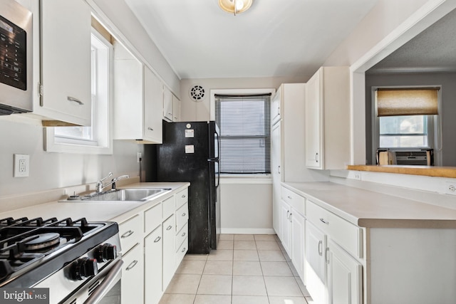 kitchen with sink, stainless steel appliances, light tile patterned floors, and white cabinets