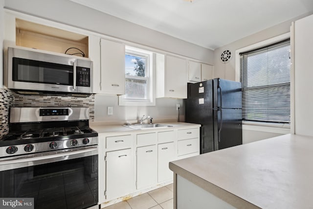 kitchen with appliances with stainless steel finishes, light tile patterned flooring, decorative backsplash, and white cabinets