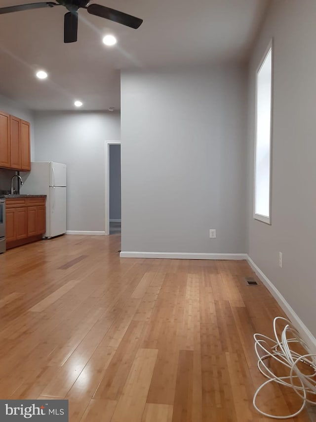 unfurnished living room with ceiling fan, light hardwood / wood-style floors, and plenty of natural light