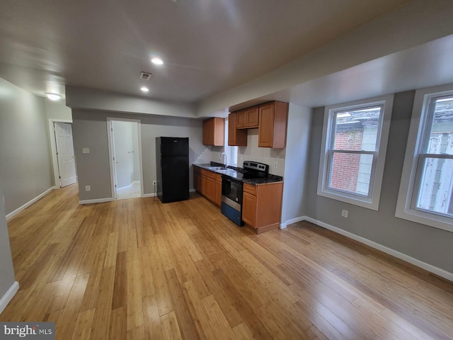 kitchen featuring black fridge, sink, light hardwood / wood-style floors, and electric stove