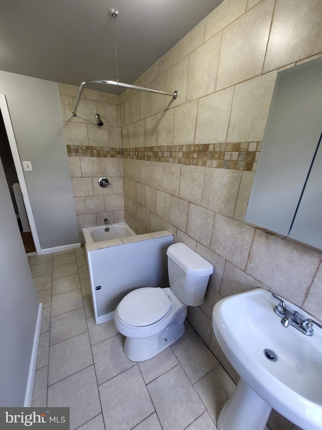 full bathroom featuring toilet, tiled shower / bath combo, tile patterned flooring, tile walls, and sink