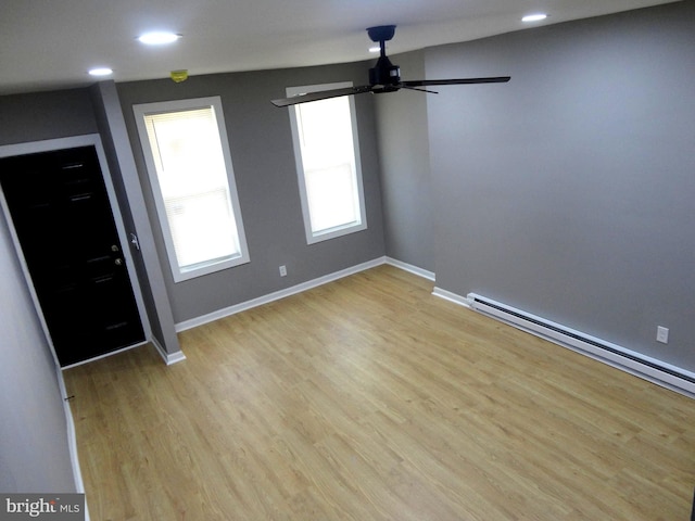 foyer entrance featuring a baseboard radiator, light hardwood / wood-style flooring, and ceiling fan