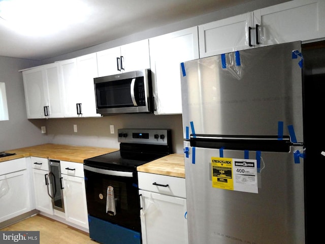 kitchen with white cabinets, stainless steel appliances, light wood-type flooring, and wood counters