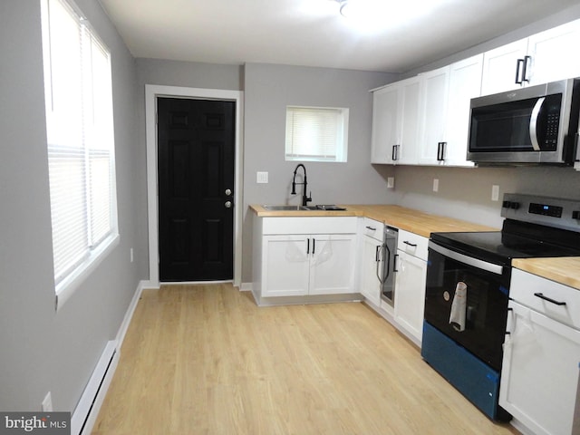 kitchen featuring wooden counters, white cabinets, black range with electric stovetop, sink, and light hardwood / wood-style flooring