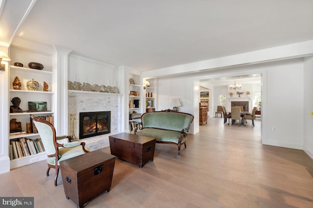 living room featuring a notable chandelier, hardwood / wood-style flooring, built in features, and crown molding