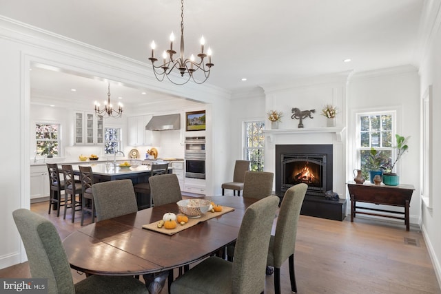 dining room featuring sink, crown molding, light hardwood / wood-style flooring, and plenty of natural light