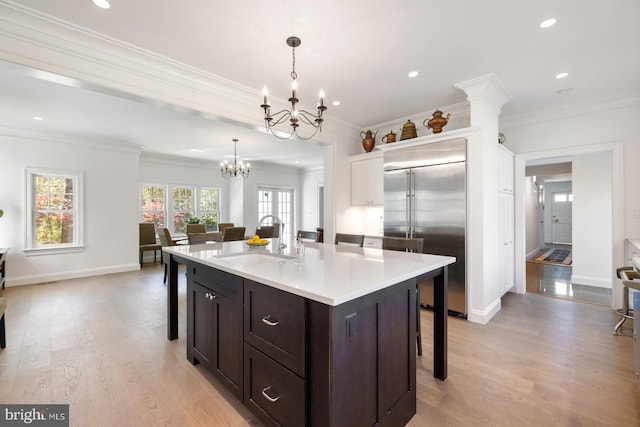 kitchen with light hardwood / wood-style flooring, sink, decorative light fixtures, and a kitchen island with sink