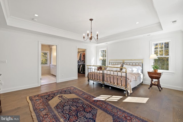 bedroom with ornamental molding, a spacious closet, ensuite bath, and dark hardwood / wood-style flooring