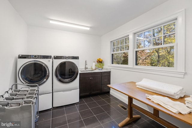 laundry room featuring sink, washing machine and dryer, cabinets, and dark tile patterned flooring