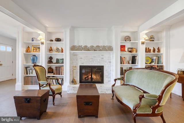 sitting room with ornate columns, a fireplace, wood-type flooring, and built in features