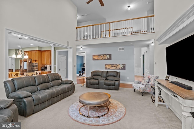 carpeted living room featuring ceiling fan, decorative columns, and a high ceiling