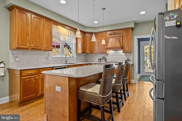 kitchen featuring light hardwood / wood-style flooring, stainless steel appliances, sink, a breakfast bar, and a center island