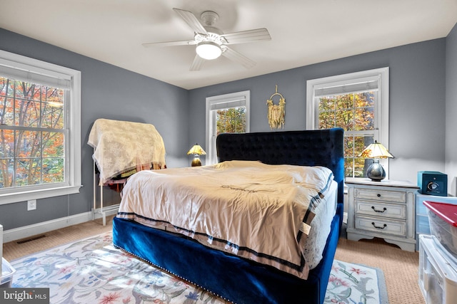 carpeted bedroom featuring multiple windows and ceiling fan