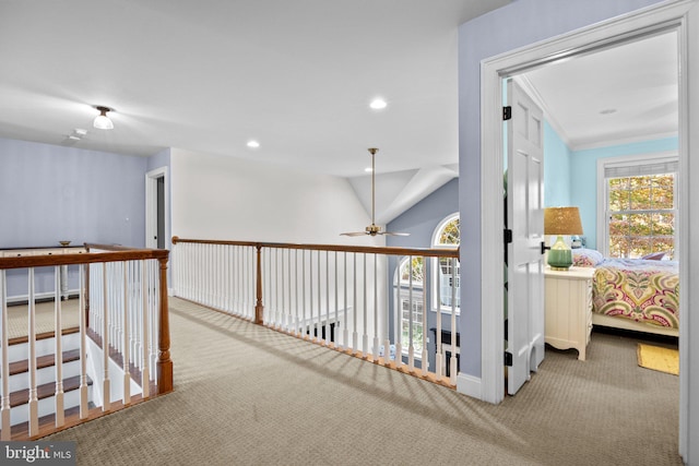 hallway featuring light carpet, ornamental molding, and vaulted ceiling