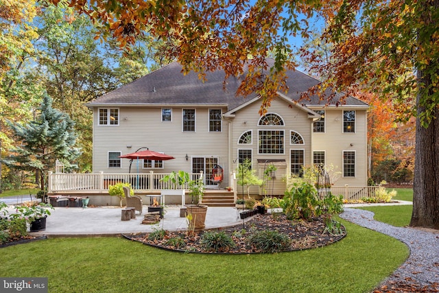 rear view of property featuring a patio, a deck, and a lawn