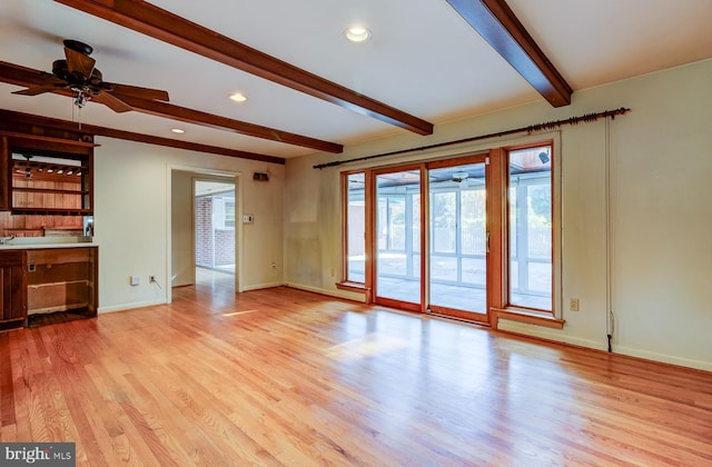 unfurnished living room with beam ceiling, light wood-type flooring, and ceiling fan