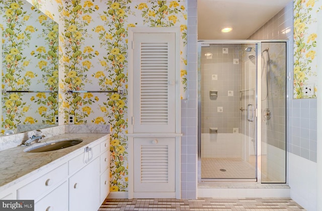 bathroom with a shower with door, vanity, and tile patterned floors