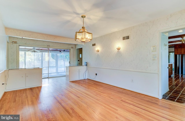 unfurnished room featuring wood-type flooring and an inviting chandelier