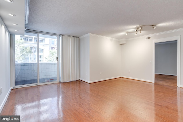 spare room with crown molding, a textured ceiling, and hardwood / wood-style flooring