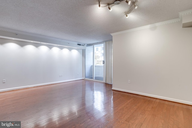 empty room with crown molding, a textured ceiling, and light hardwood / wood-style flooring