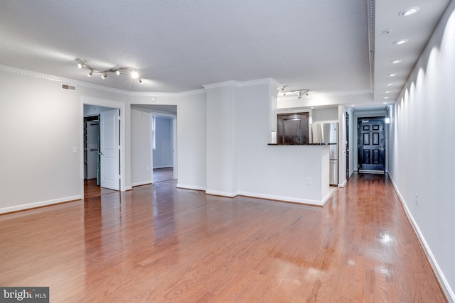 unfurnished living room featuring hardwood / wood-style flooring, ornamental molding, and a textured ceiling