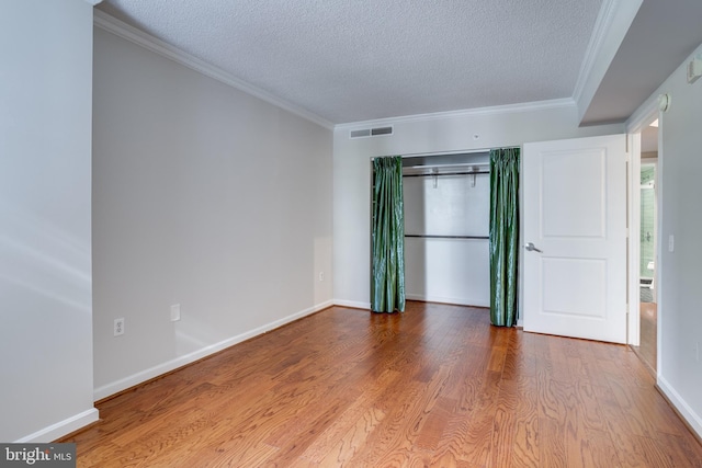 unfurnished bedroom with light hardwood / wood-style floors, a textured ceiling, and ornamental molding