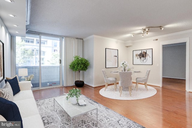 living room featuring ornamental molding, a wall of windows, hardwood / wood-style floors, and a textured ceiling