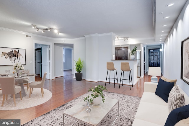 living room featuring ornamental molding, a textured ceiling, and hardwood / wood-style floors