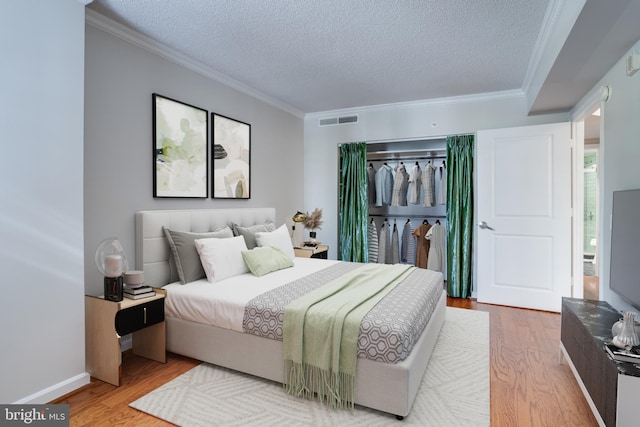 bedroom with hardwood / wood-style flooring, a textured ceiling, and ornamental molding