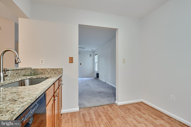 kitchen featuring sink, light stone counters, dishwasher, and light hardwood / wood-style floors