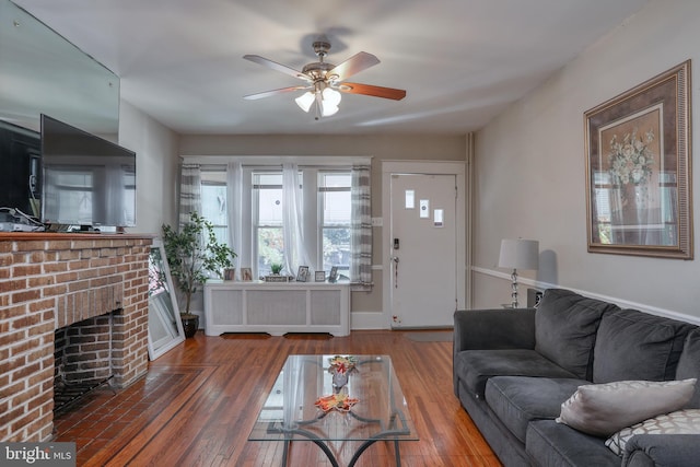 living room with hardwood / wood-style floors, ceiling fan, and a fireplace