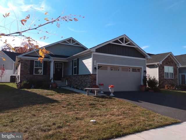 craftsman-style house featuring cooling unit, a front lawn, and a garage