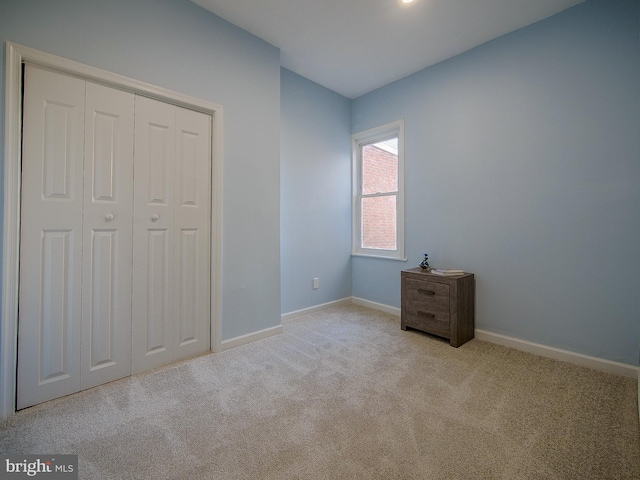 unfurnished bedroom with a closet and light colored carpet